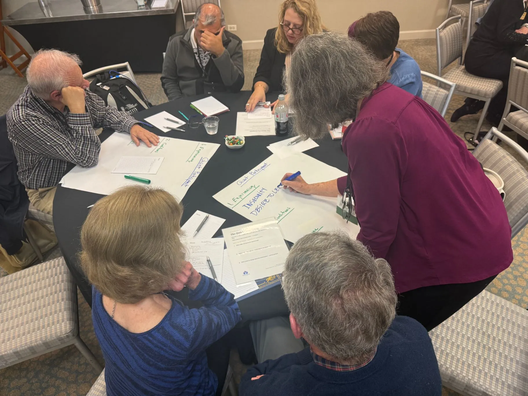 A small group working around a table with flip chart paper and worksheets during a workshop