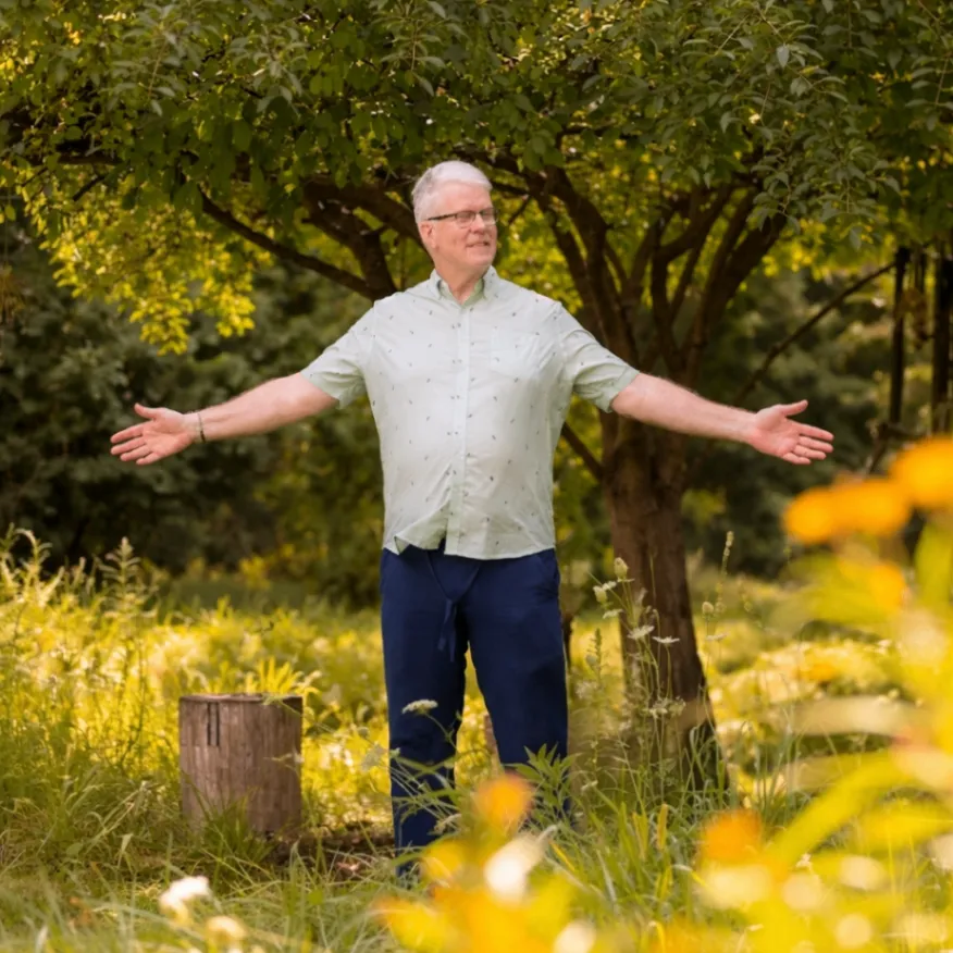 Michael Shoultz standing outdoors with his arms open